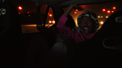 a person in a car with their hands up in the air