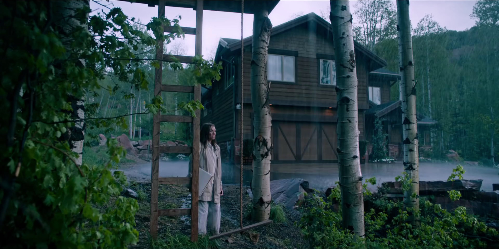 a man standing in front of a wooden cabin