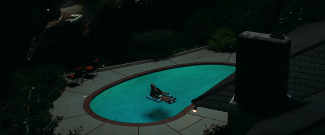 a person sitting on a bench in front of a swimming pool