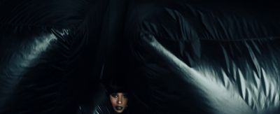 a woman hiding behind a black blanket in the dark