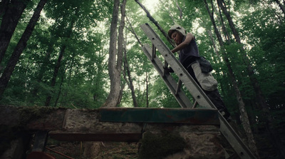 a person climbing up a ladder in the woods