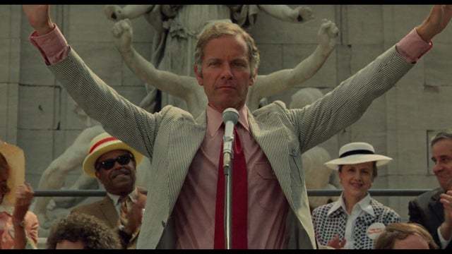 a man standing in front of a microphone surrounded by people