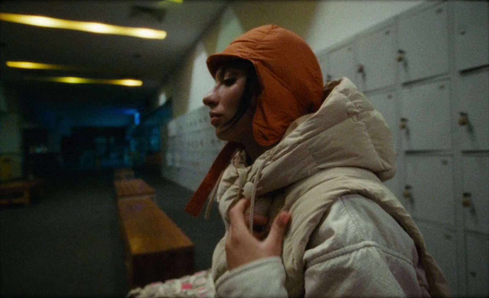 a woman in a hooded jacket standing in a hallway