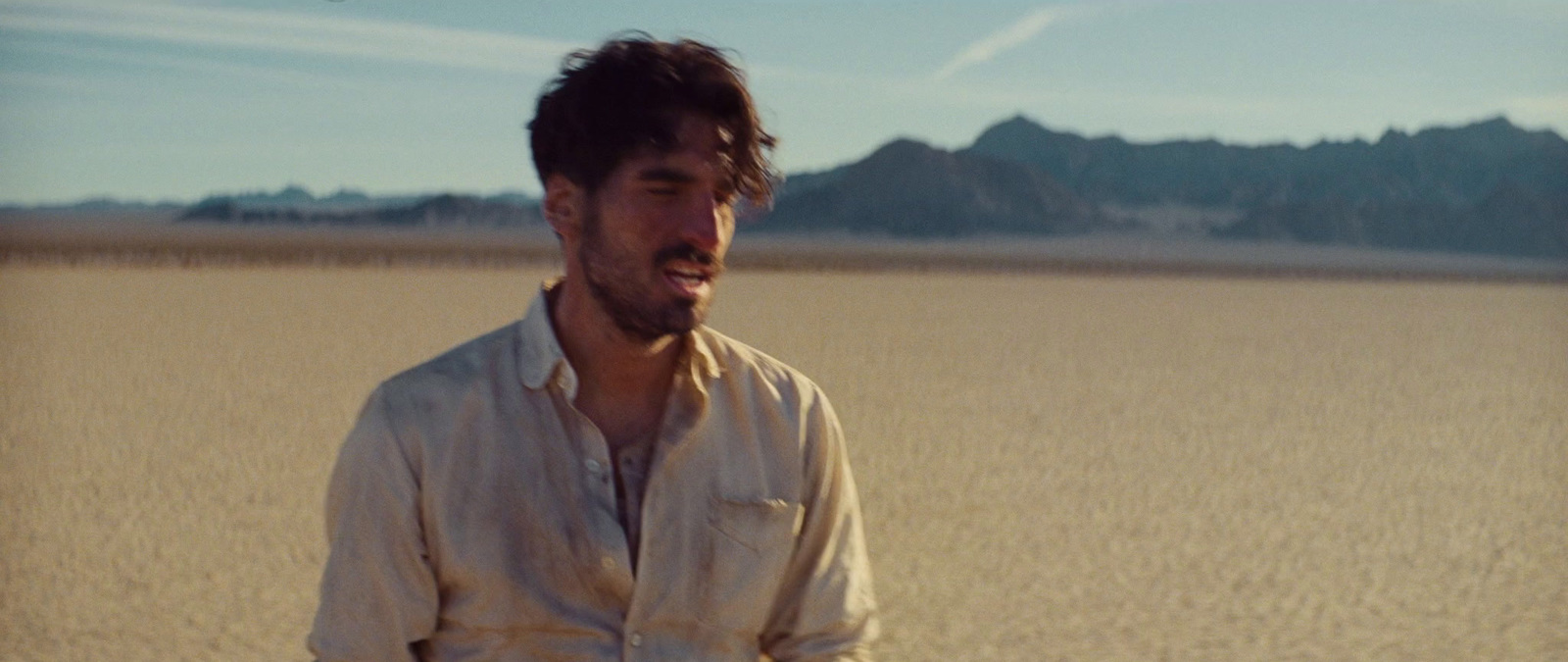 a man standing in a field with mountains in the background