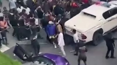 a group of people standing around a white car