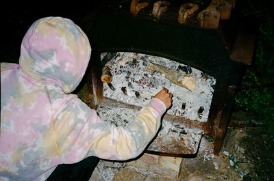 a person in a pink and yellow hoodie is putting something in a brick oven