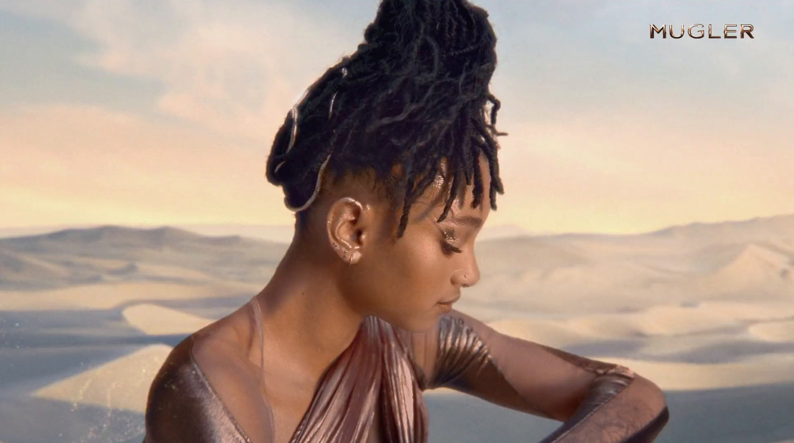 a woman with dreadlocks sitting in a desert