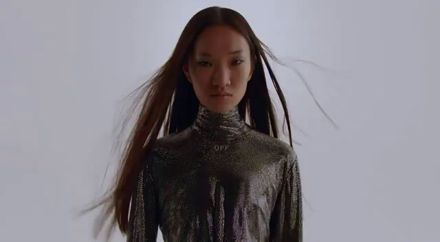 a woman with long hair standing in front of a white background