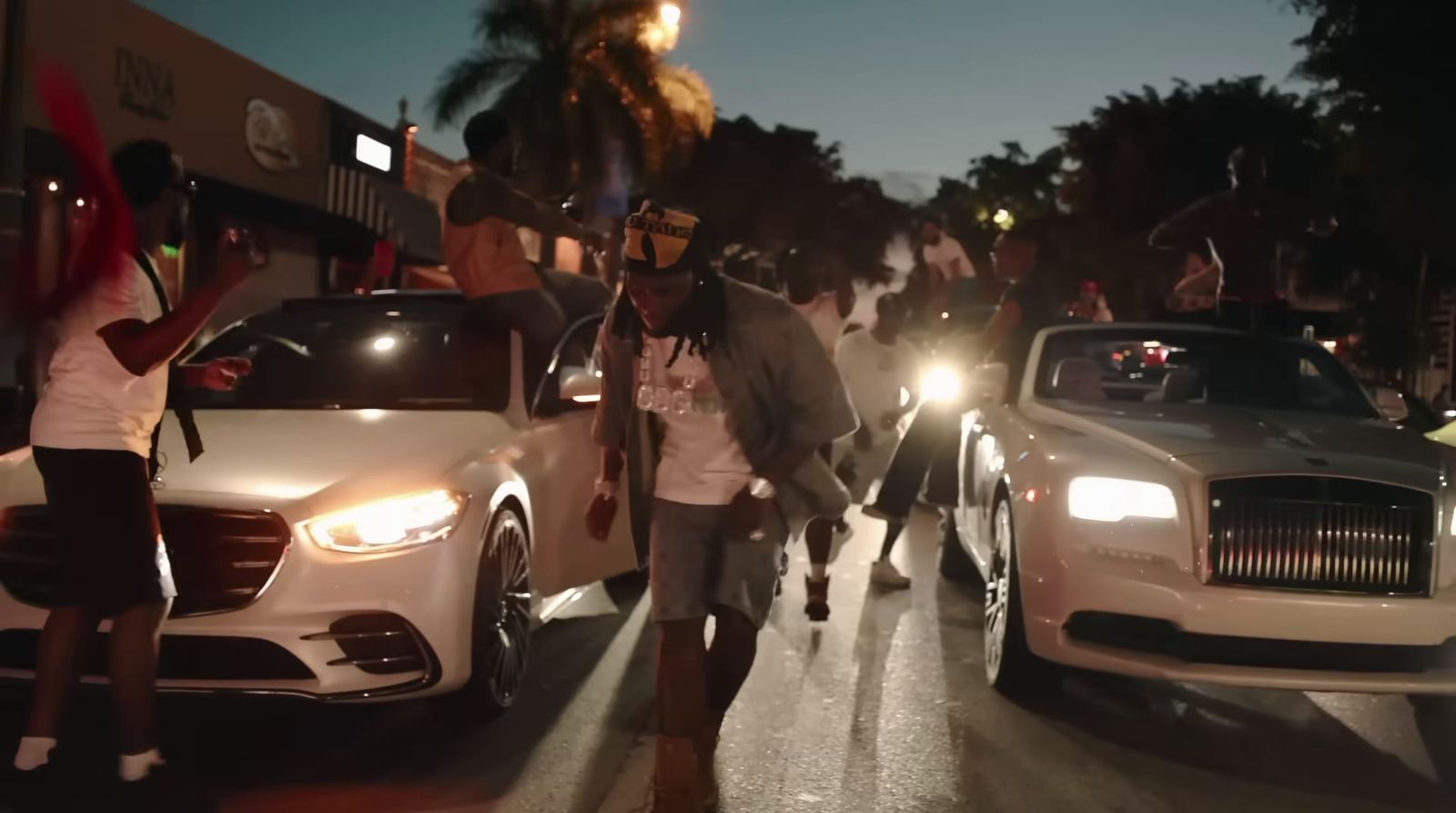 a group of people walking down a street next to parked cars