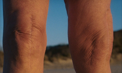 a close up of a person's legs on the beach