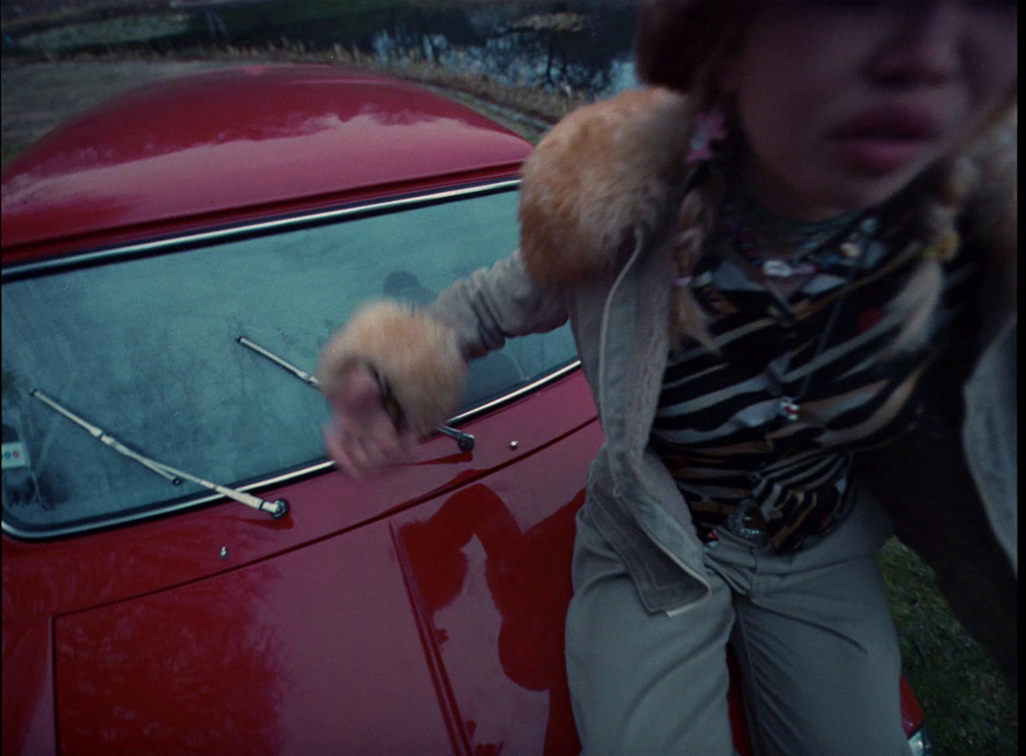 a woman standing next to a red car