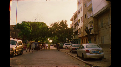 a group of people walking down a street next to parked cars