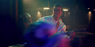 a man playing a guitar in a dark room