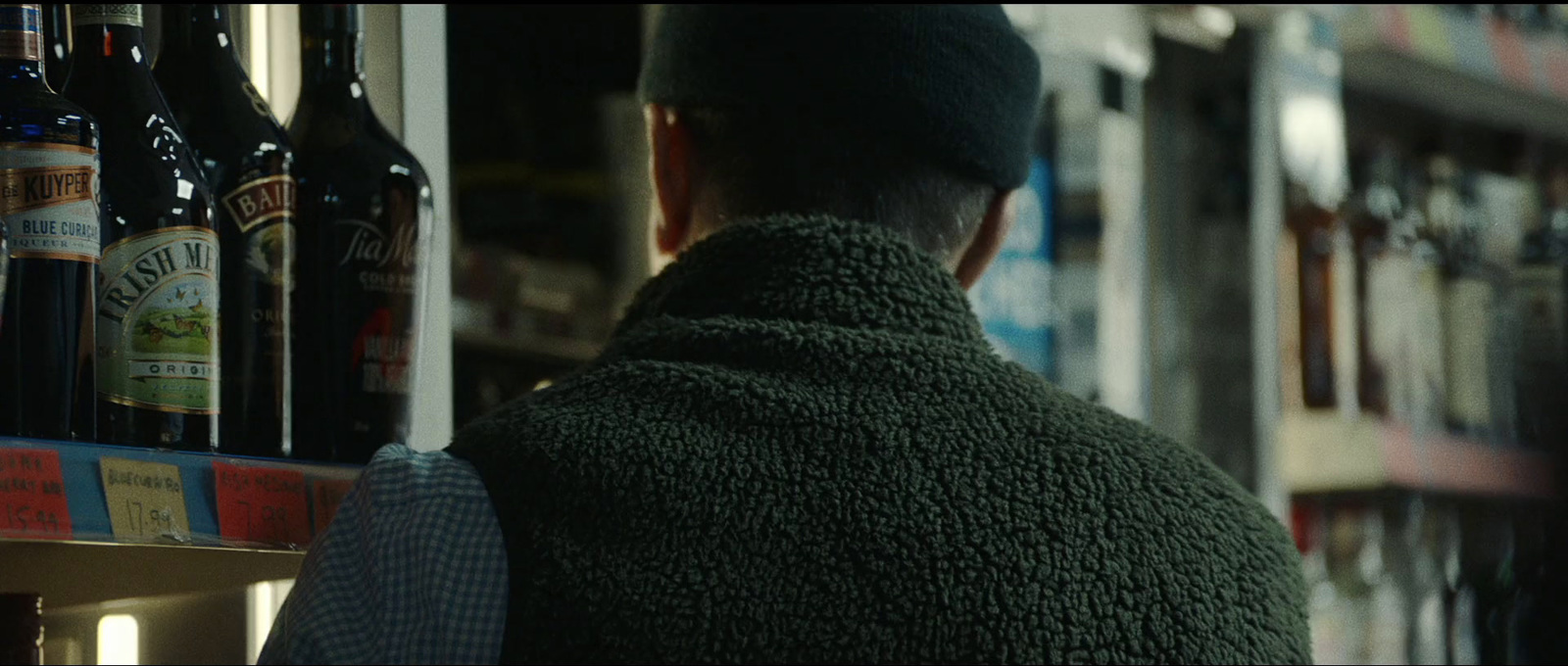 a man standing in front of a shelf of beer bottles