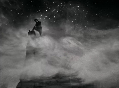 a black and white photo of a man standing on top of a mountain