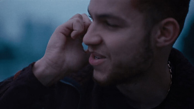 a man talking on a cell phone while wearing a black jacket