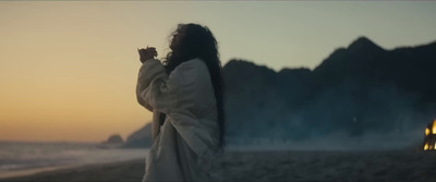 a woman with long hair standing on a beach