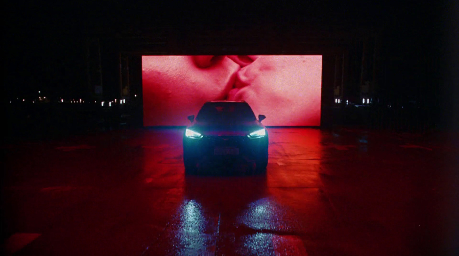 a car is parked in front of a large screen