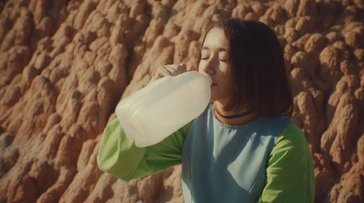 a woman drinking water from a plastic bottle