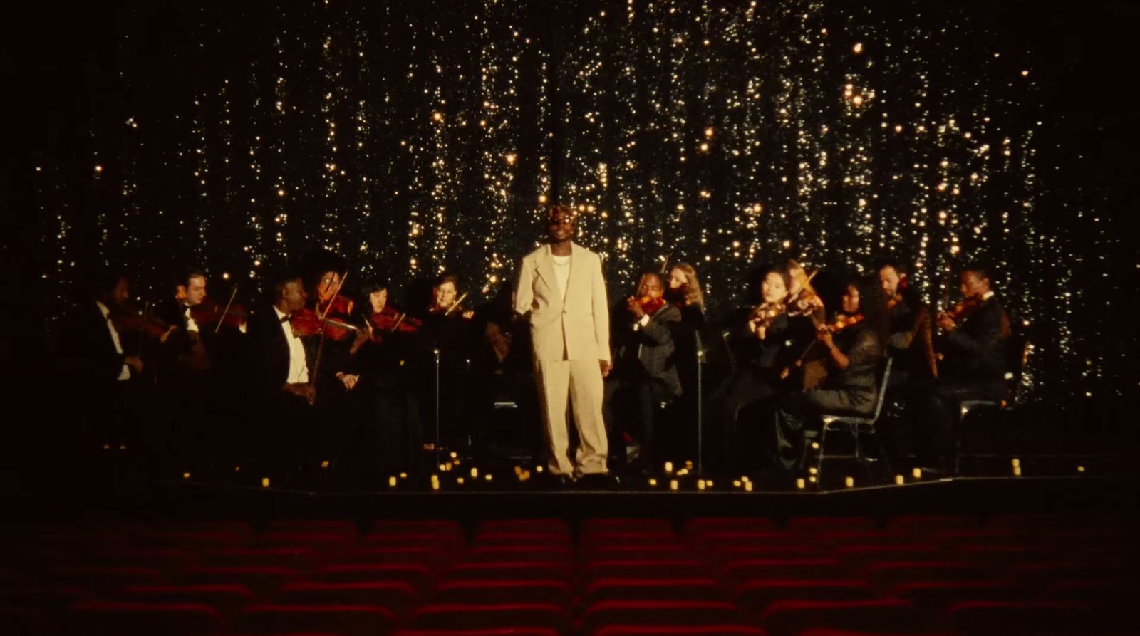 a man in a white suit standing on a stage