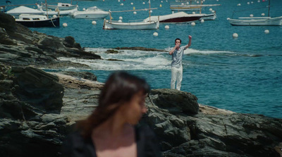 a man standing on top of a rock next to a body of water