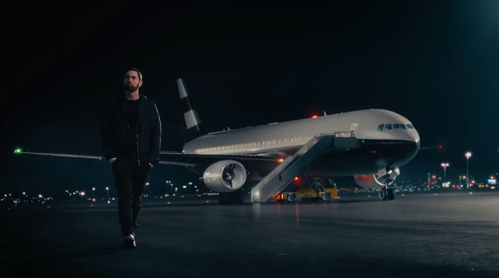 a man standing in front of an airplane at night