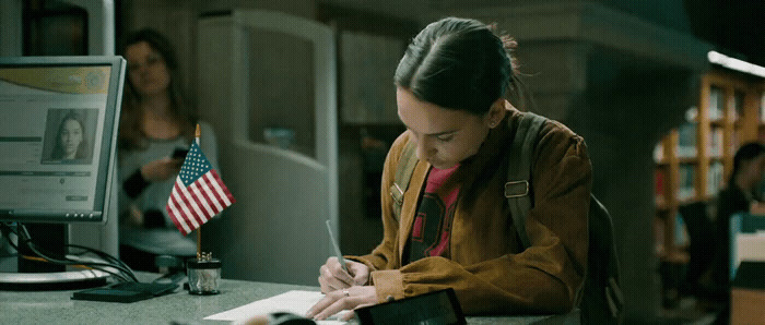 a woman sitting at a desk writing on a piece of paper