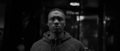 a man standing in a dark room with a hoodie on