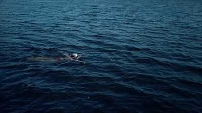 a person swimming in the ocean with a dog