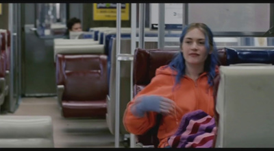 a woman in an orange jacket sitting on a bus