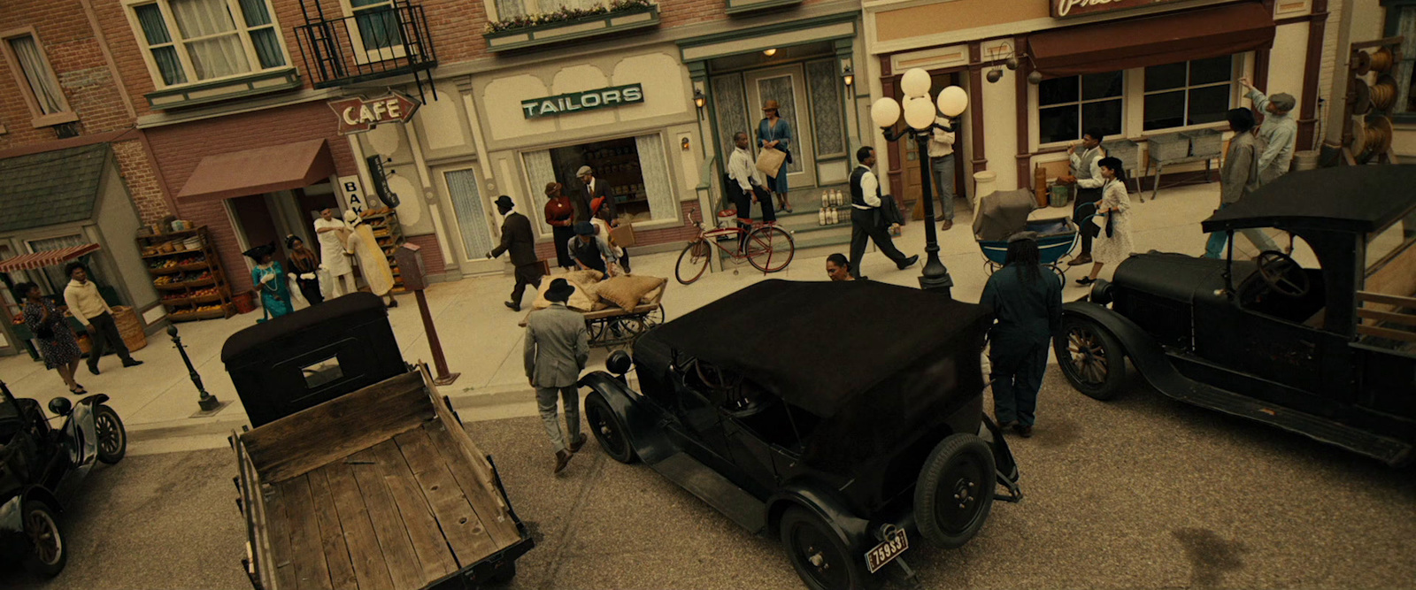 a group of people walking down a street next to parked cars