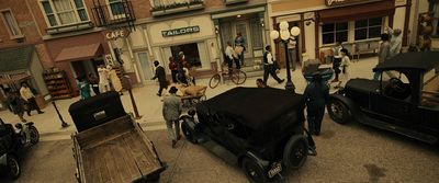 a group of people walking down a street next to parked cars