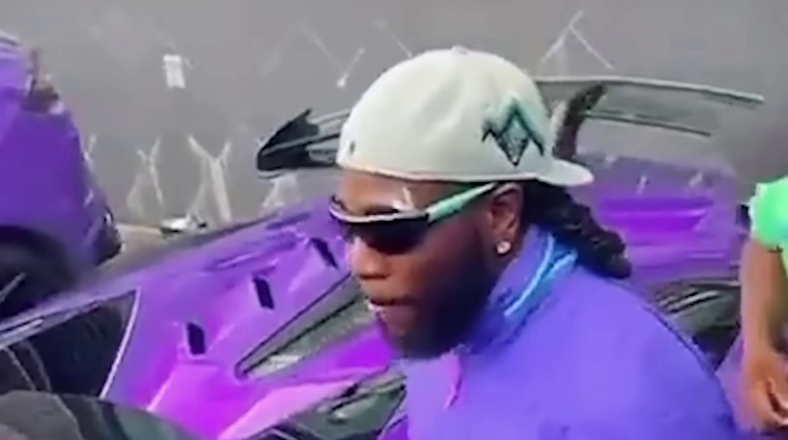 a man in a hat and sunglasses sitting on a purple car