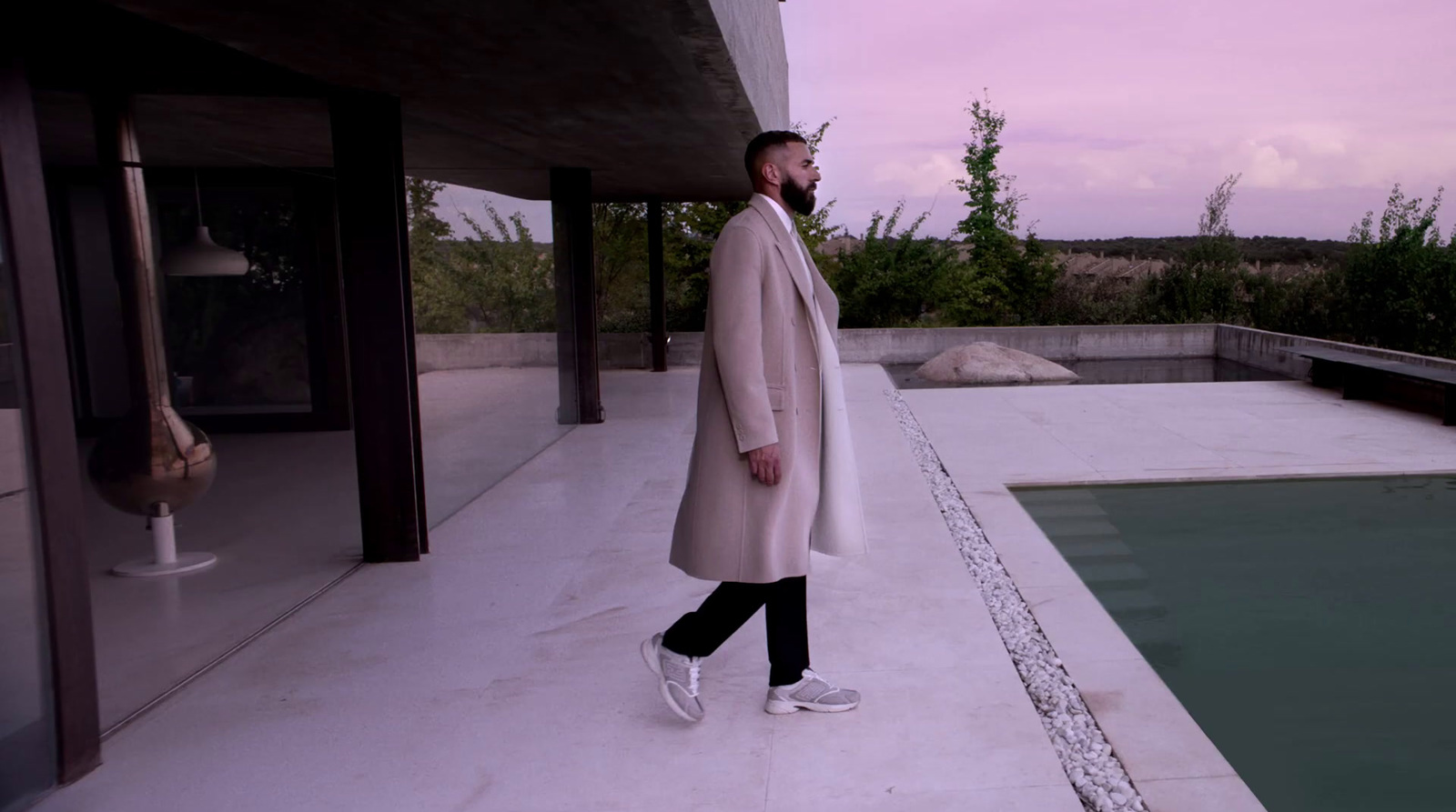 a man in a white coat is walking near a pool