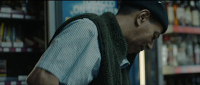 a man in a hat and vest standing in front of a bookshelf