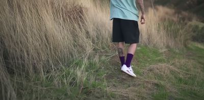 a man walking through tall grass with a frisbee in his hand