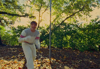 a man in white pants and a sweater is standing in leaves