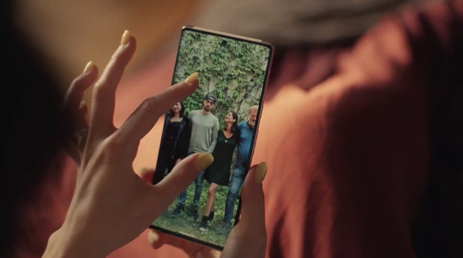 a woman holding a cell phone with a picture of a group of people on it