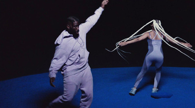 a man standing next to a woman on top of a blue floor