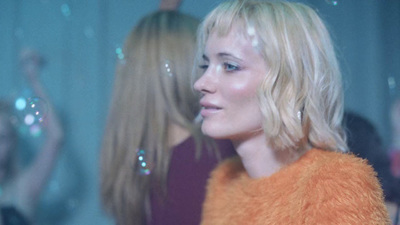 a woman with blonde hair wearing an orange jacket