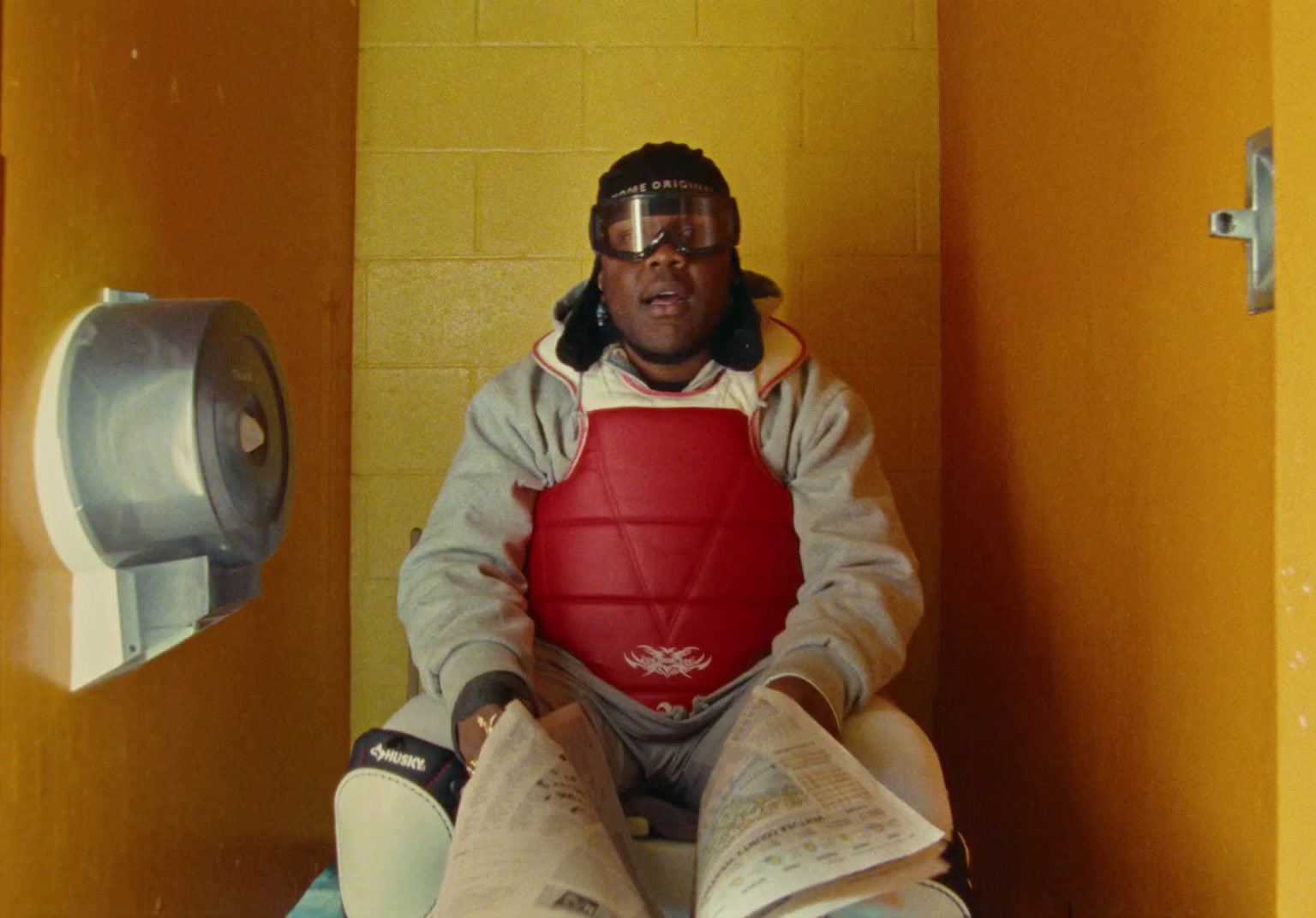 a man sitting on a toilet reading a newspaper