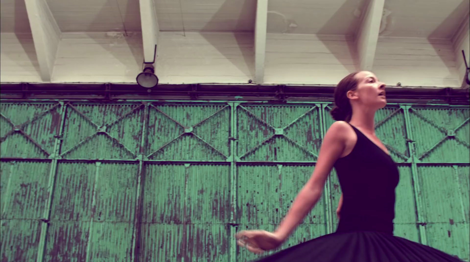 a woman in a black dress standing in front of a green wall