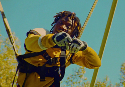 a man in a yellow jacket holding onto a yellow pole