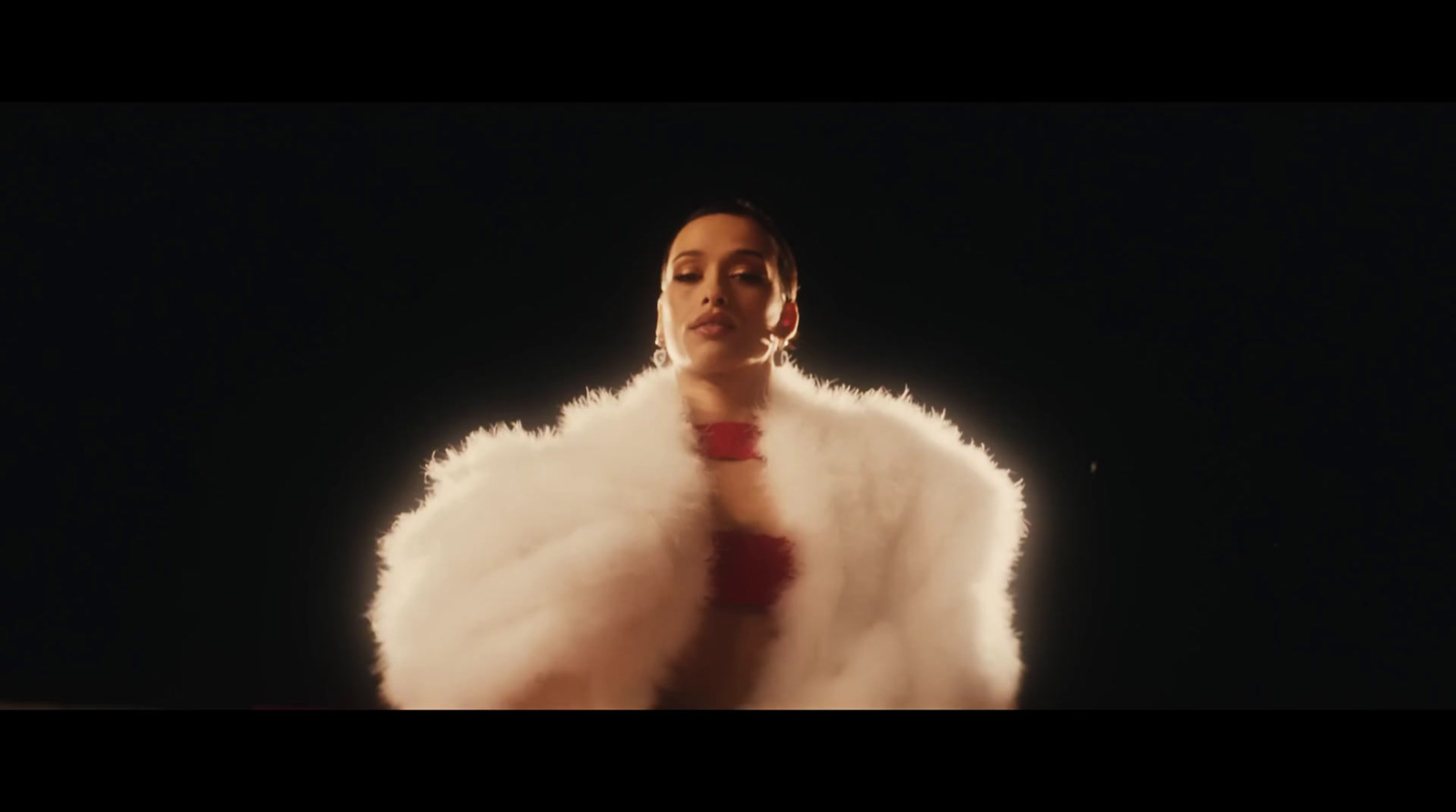 a woman in a white fur coat standing in the dark