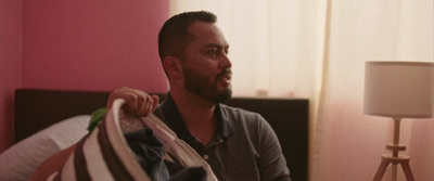 a man sitting on a bed holding a bag