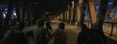 a group of people walking across a bridge at night