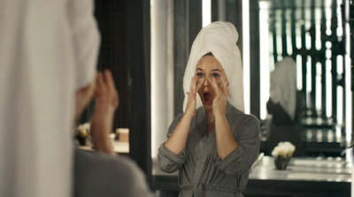 a woman with a towel on her head looking in a mirror