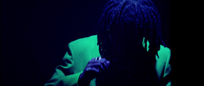 a man with dreadlocks standing in a dark room