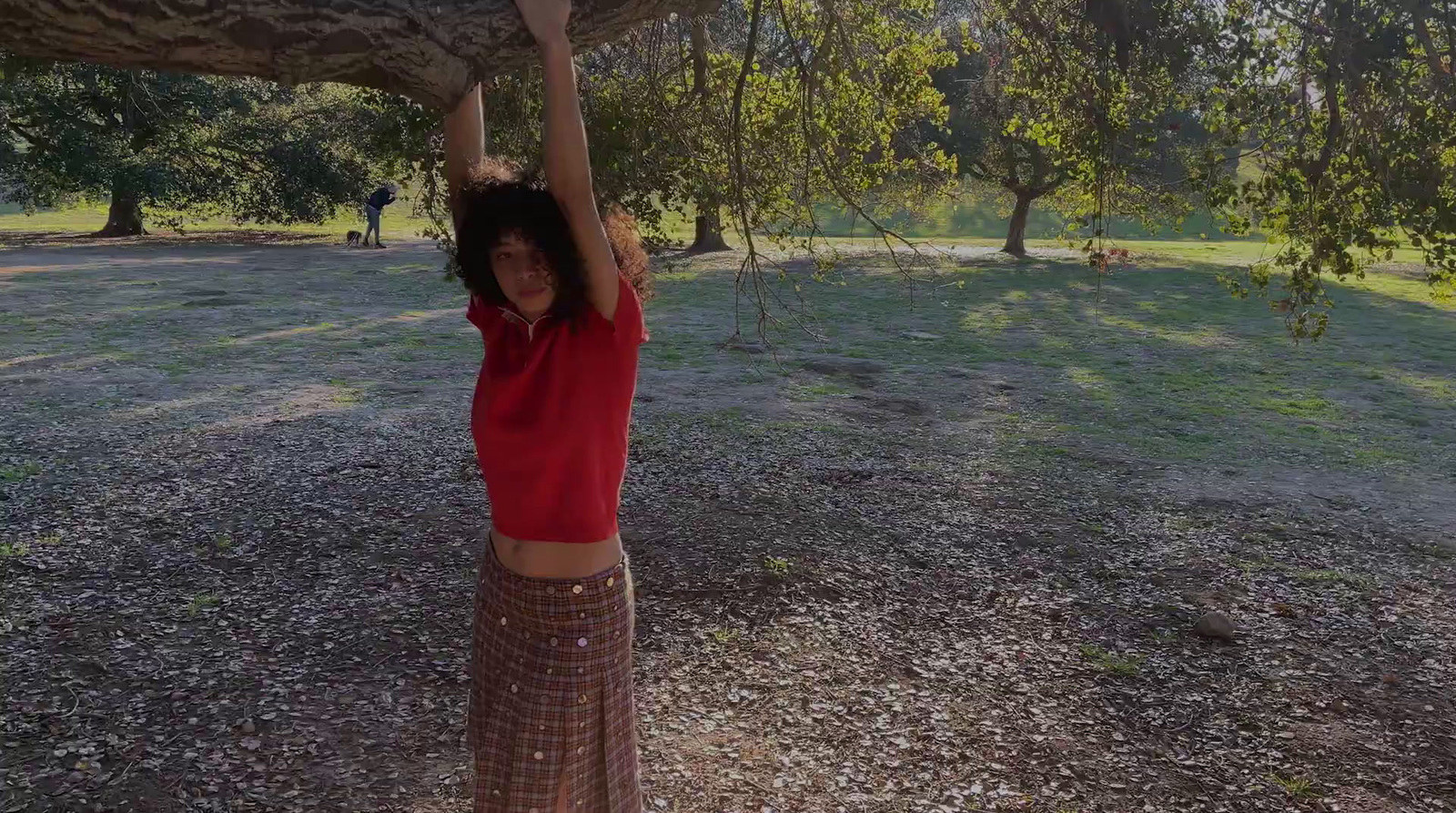 a woman in a red shirt is holding a tree branch