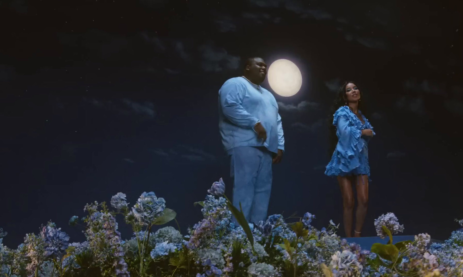 a man and a woman standing in a field at night